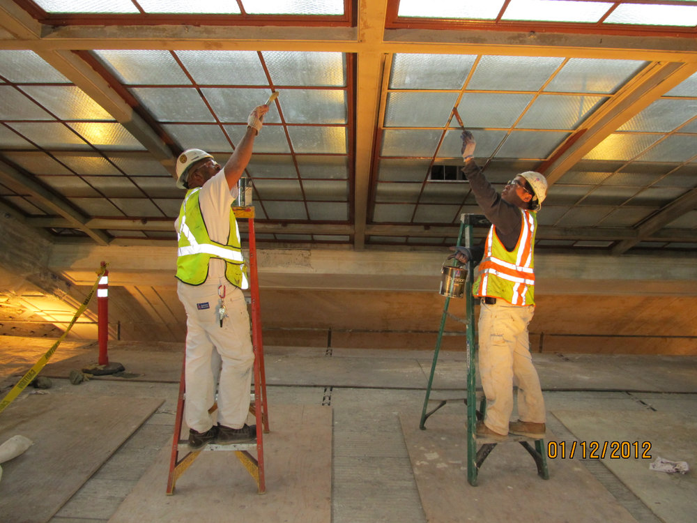 Two workers on ladders at an interior construction area in The Union Depot